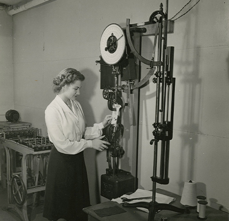 A woman utlizes a piece of textile equipment.