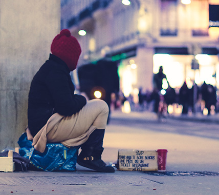 Photo a person sitting on a corner of a busy street with a cardboard sign.