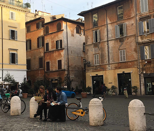 Students sitting together on a bench outside in a foreign city.