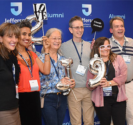 A group photo of Jefferson alumni at an event posing together with fun props like sunglasses and balloons.