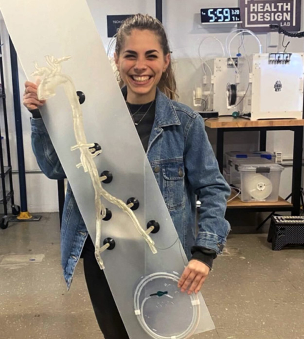 Student Eva Varotsis stands in a laboratory holding the full-scale aorta model that she created for Jefferson’s vascular surgery department in front of her while smiling at the camera.