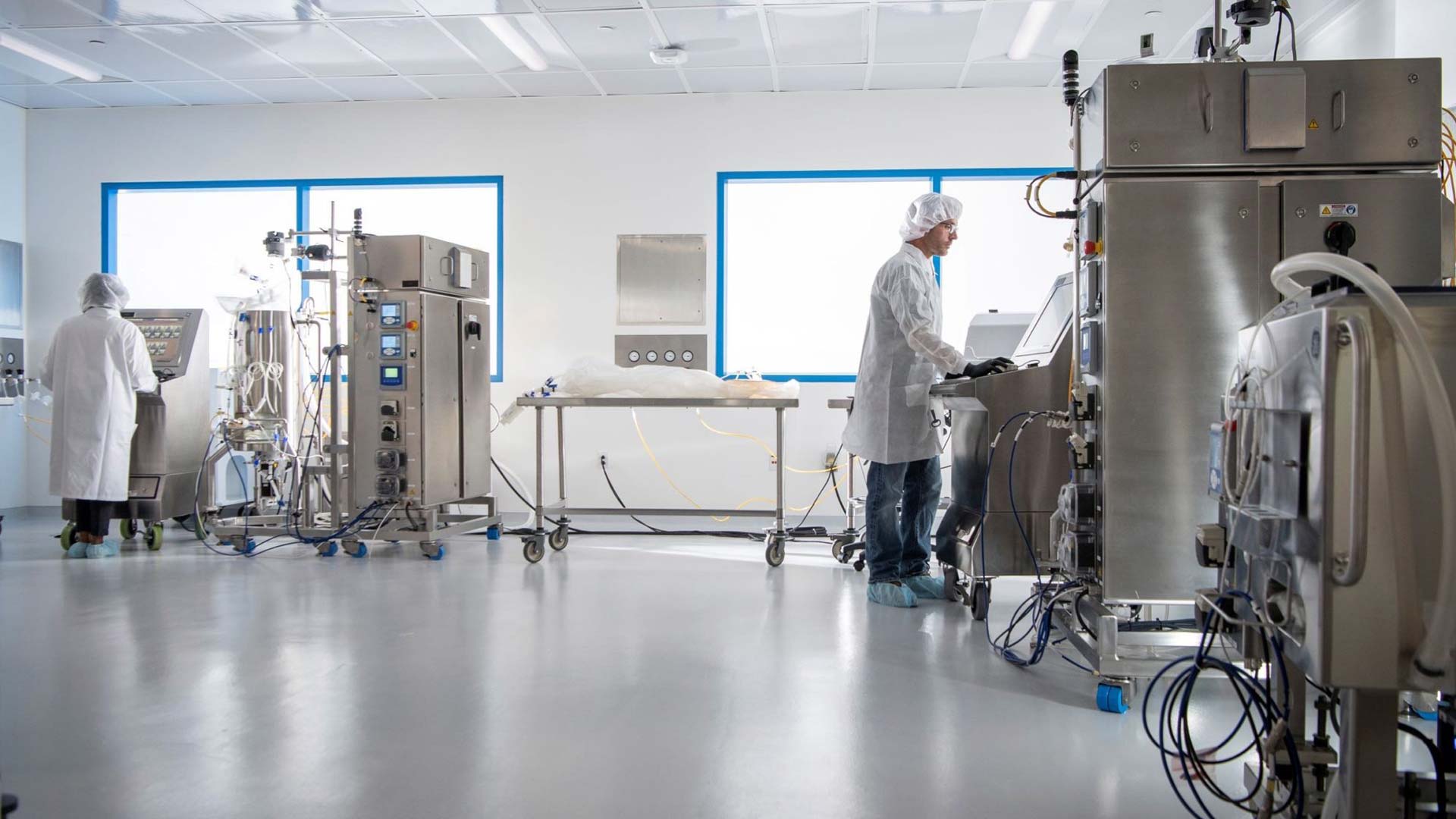 Workers in white lab coats utilize the various machines within JIB’s manufacturing facility. 