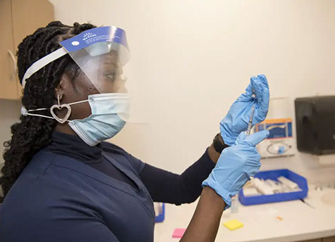 Nurse Darlene Brodie of Jefferson Health prepping the COVID-19 vaccine using a syringe and vial.