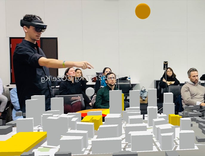 A student utilizes augmented reality while a group of students look on in the background inside the urban design studio at Jefferson, taught by Dr. Du.