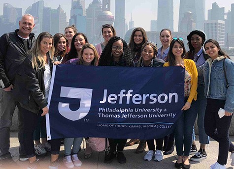 Global fashion enterprise and fashion management and merchandising students hold up a Jefferson banner in China.