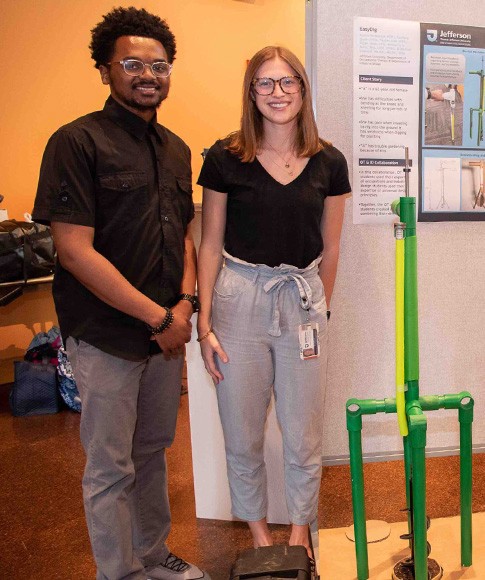 Members of the EasyDig team stand with the prototype of the tool along with a poster of their concept at the 2023 Design Assistive Device Project presentation.